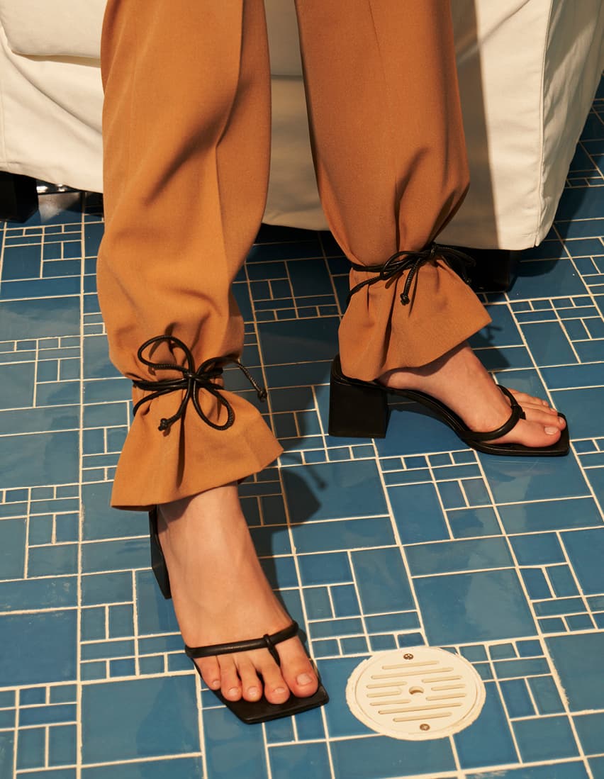A model wearing lace-up sandals tied over pants – close up