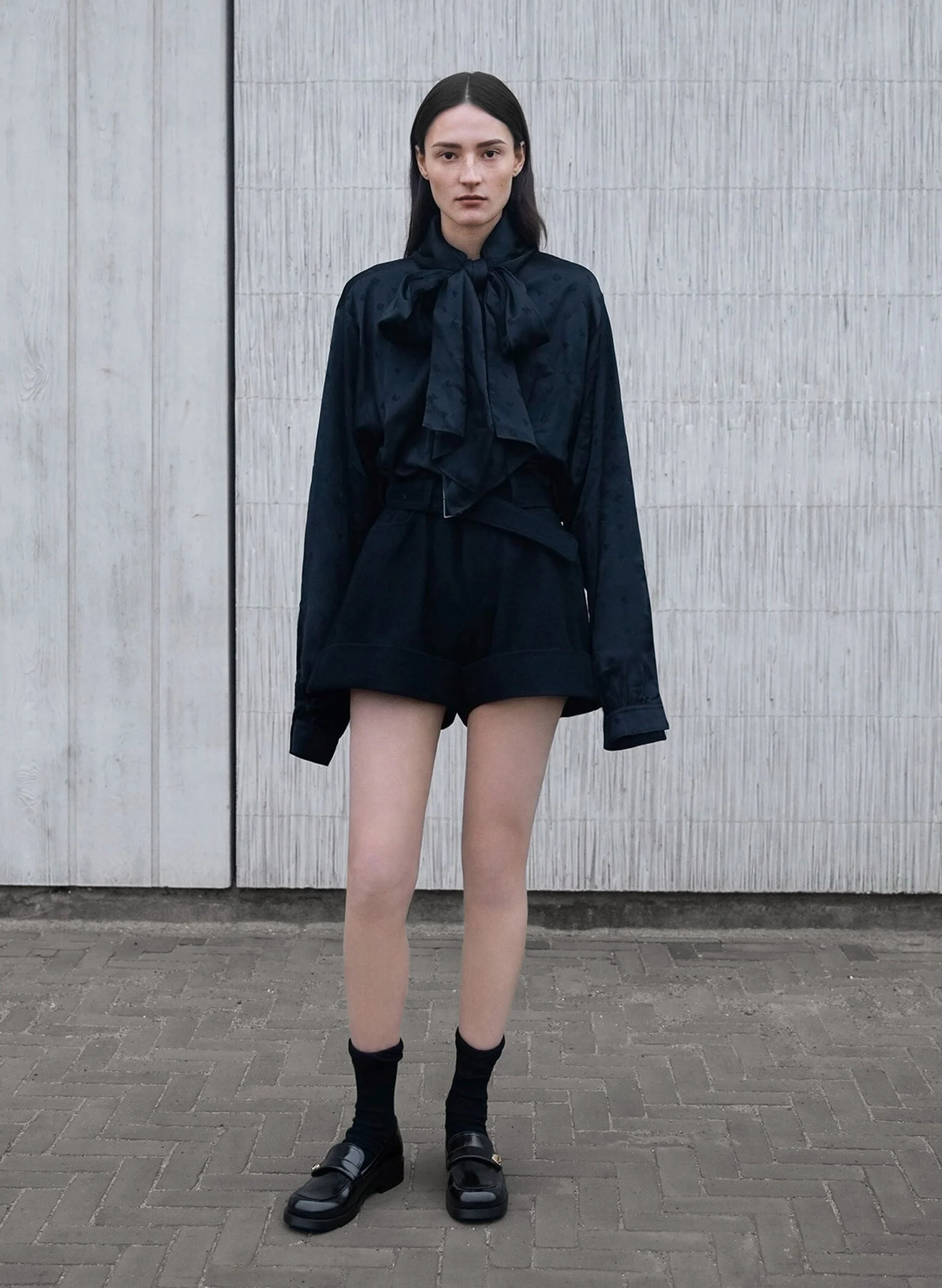 Black metallic-buckle strap loafers paired with matching black socks.