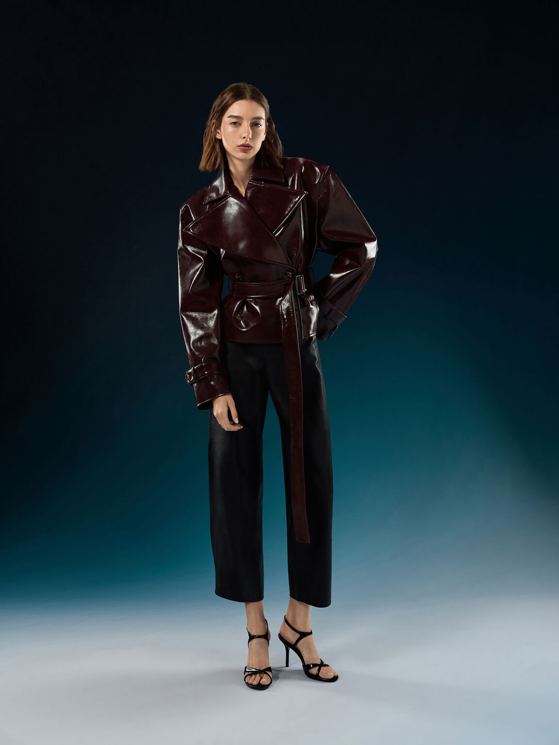 Black crossover stiletto sandals paired with a leather jacket and cropped tailored trousers.
