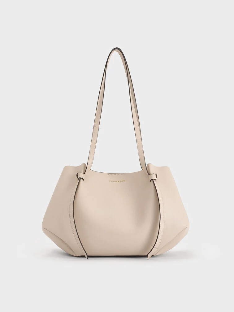 The Calla tote bag in oat with the side magnetic clasps folded in to create a geometric-like shape 