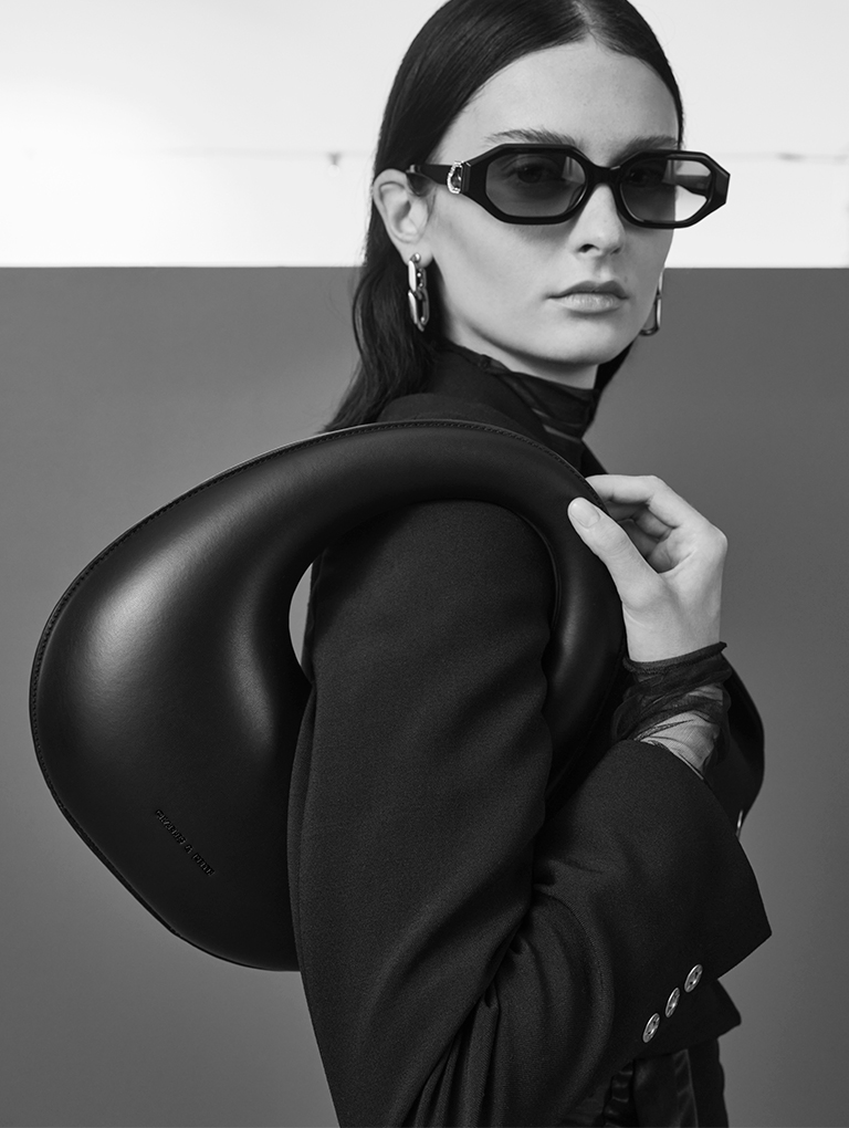 Women’s Sculptural Top Handle Moon Bag in black; Gabine Swarovski Crystal Oval Sunglasses in black; Gabine Chain-Link Drop Earrings in silver – CHARLES & KEITH