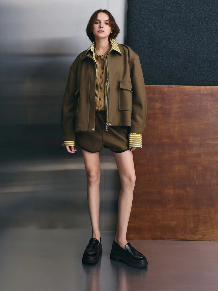 Black platform penny loafers paired with an olive-green shacket and matching short co-ord.