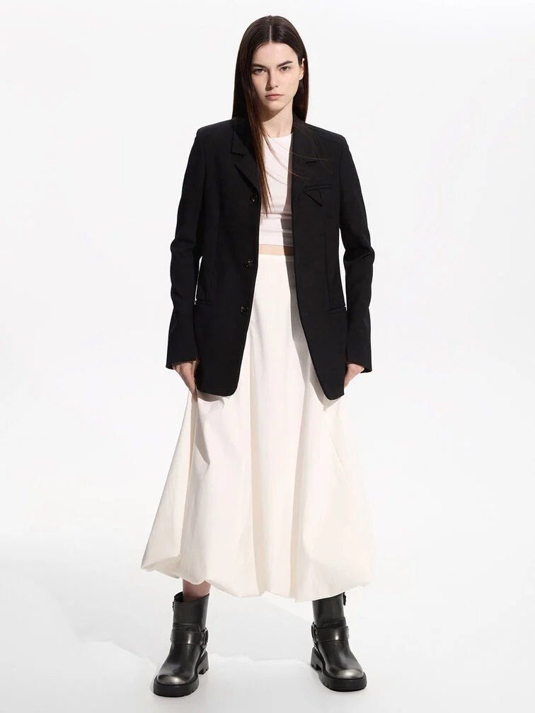 Chunky black ankle boots styled with a matching blazer layered over a white dress.