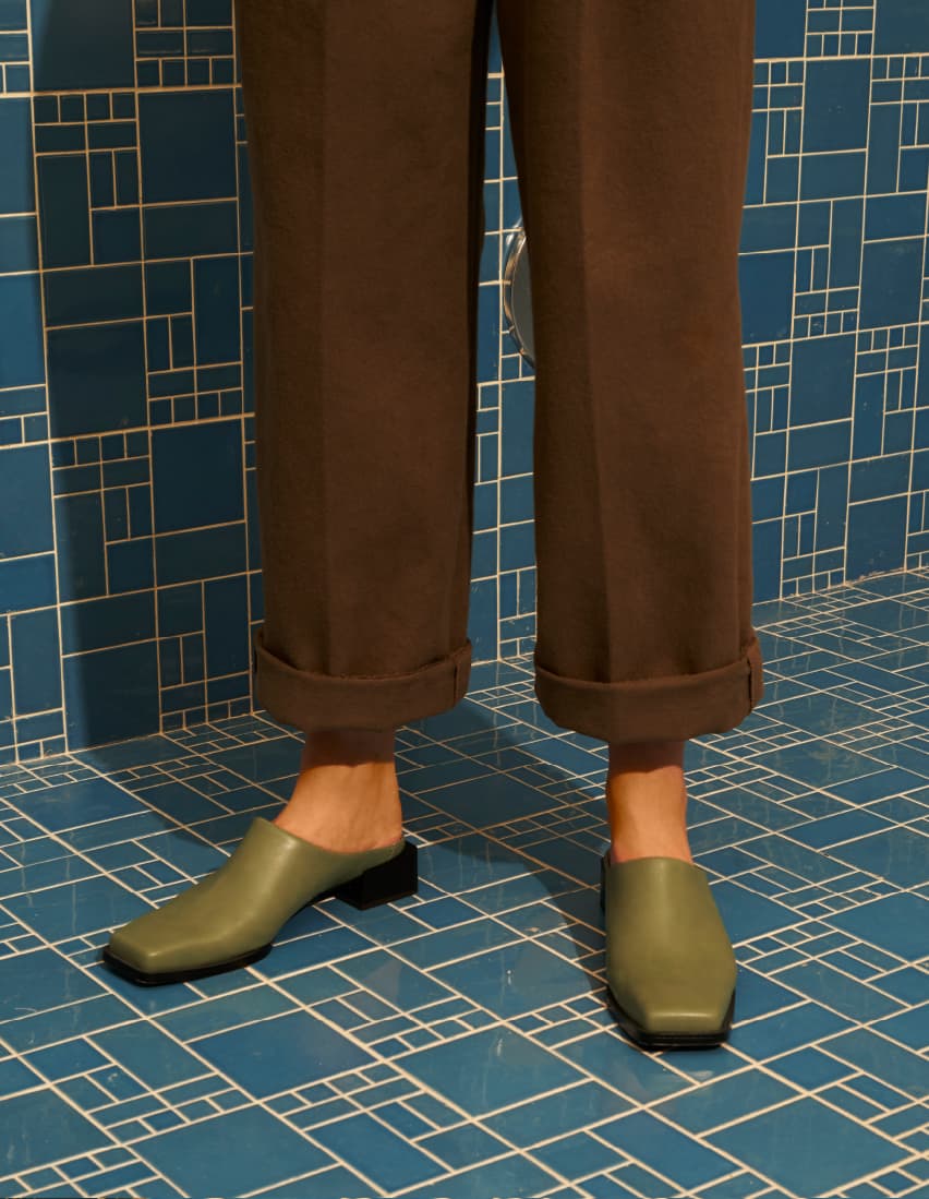 A model wearing tailored pants with square toe mules – close up