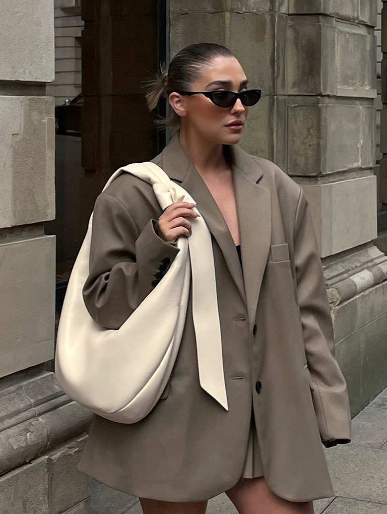 Women’s Toni Knotted Curved Hobo Bag in chalk and Recycled Acetate Angular Shield Sunglasses in black, as seen on Hannah Whiting – CHARLES & KEITH