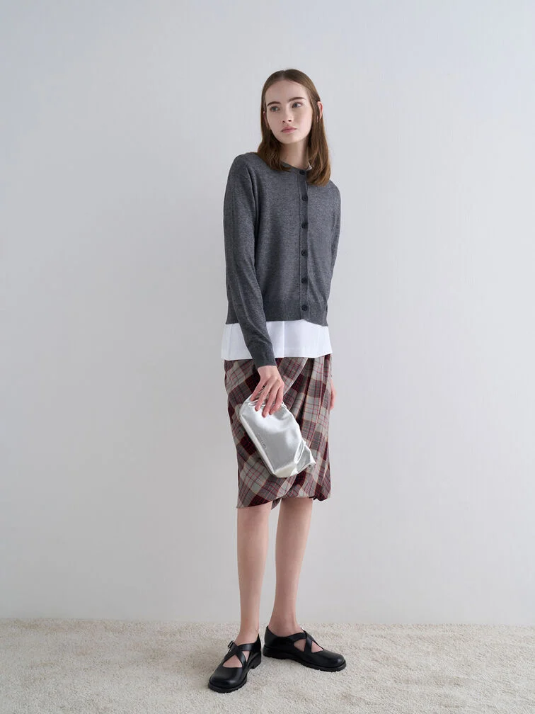 Clutch held vertically from the side with the thumb at the back, offering an unconventional way to carry smaller bags.