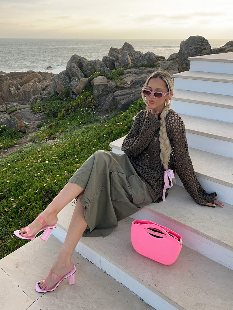 Women’s Cocoon Curved Handle Bag in pink; Fia Geometric Heel Mules in light pink; Gabine Recycled Acetate Oval Sunglasses in violet, as seen on Sofia Coelho - CHARLES & KEITH