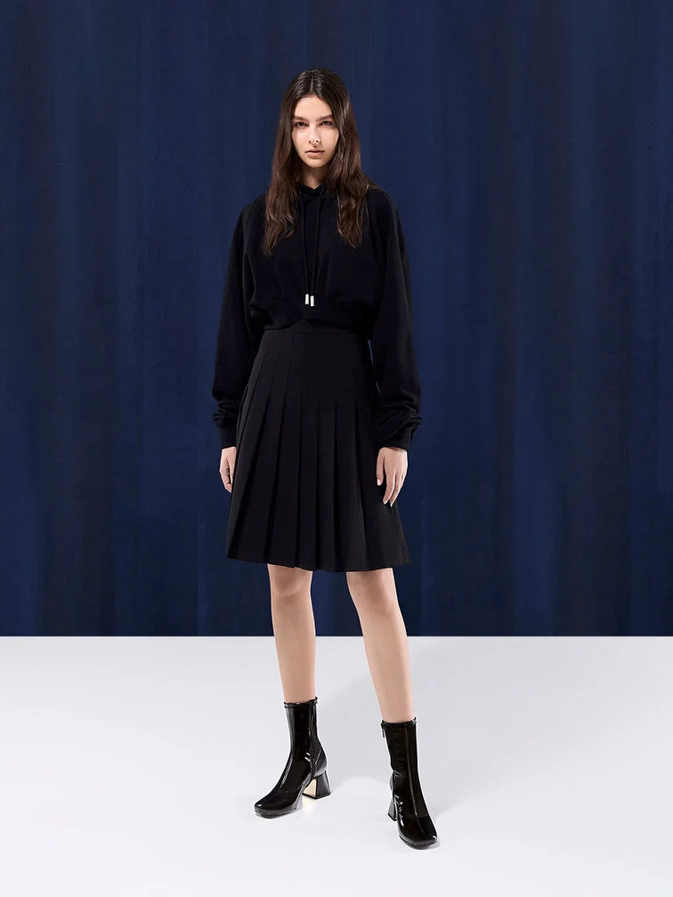 Patent block-heel ankle boots paired with a long-sleeve blouse and pleated midi skirt.