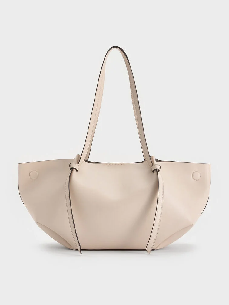 The Calla tote bag in oat with the side magnetic clasps folded out creates a wider and slouchier shape