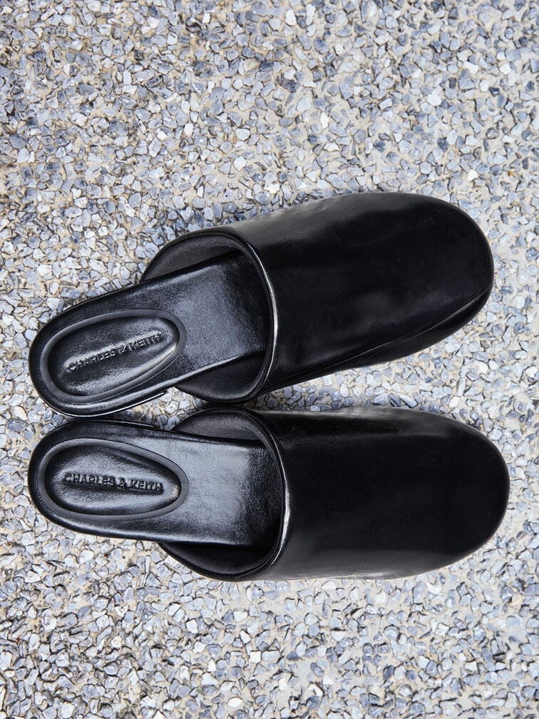 Black flat mules with a backless, slip-on design.