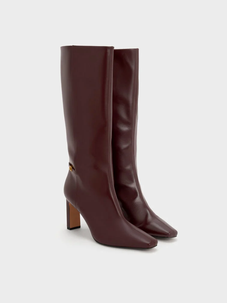 Burgundy knee-high boots add a pop of rich colour to any winter white outfit.
