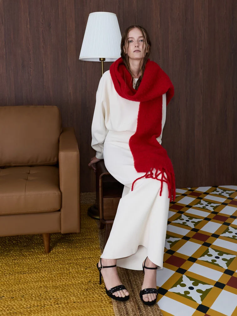 A crimson red scarf creates a striking visual contrast with a Cloud Dancer white maxi dress.  