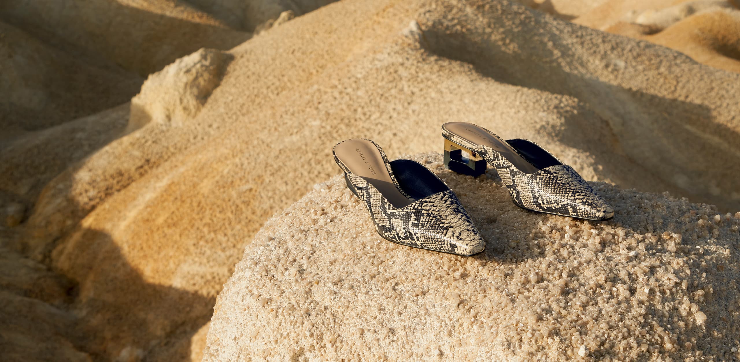 Women’s snakeskin print sculptural chrome heel mules