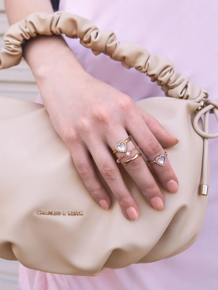 Showcasing an elegant 3-ring stack featuring a heart gemstone ring, a delicate crystal ring and a slim band on the middle finger, and a heart gemstone ring on the index finger with varying placement