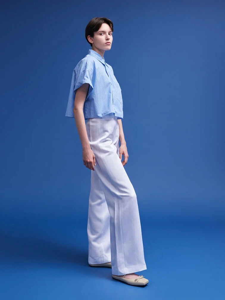 A woman wearing beige bow square-toe ballet mules, styled with wide-leg pants and a short-sleeved blouse for a polished, office-ready look.