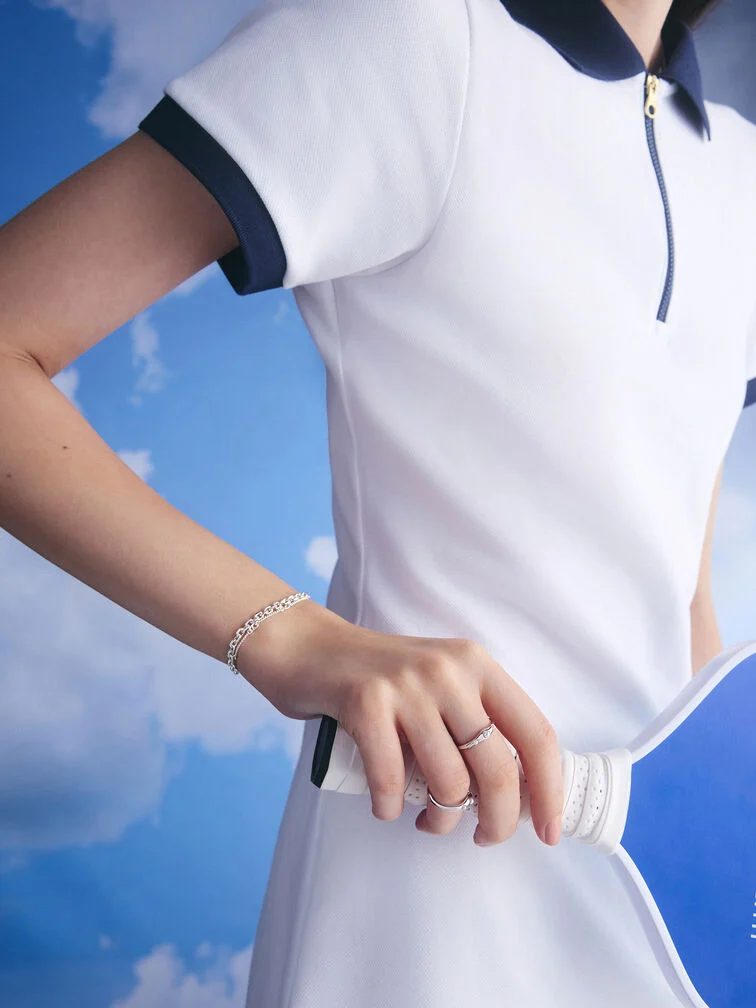 Silver double-chain bracelet styled with a two-tone polo dress for pickleball.