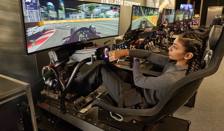 Kareen Kaur enjoying a racing simulator at The F1® Exhibition Singapore - CHARLES & KEITH